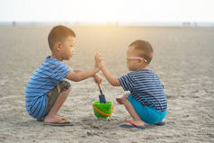 日落时男孩子们在沙滩上玩沙子