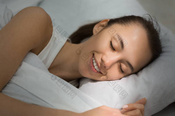 愉快的睡眠。女孩睡在床上与阳光在脸上