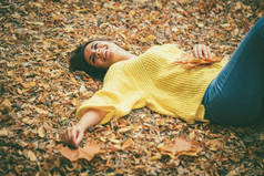 年轻的妇女躺在金黄叶子在秋天公园
