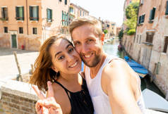 愉快的夫妇自拍与智能手机在威尼斯的运河著名的欧洲城市在意大利夏季假期旅游环游欧洲度假爱和蜜月概念.