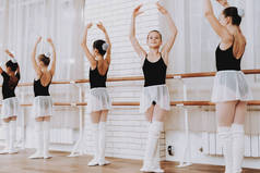 室内年轻女孩团体的芭蕾培训。古典芭蕾。巴莱丽娜·图图的女孩。室内训练。可爱的舞者大厅里的表演。舞蹈练习。穿白色衣服的女孩.