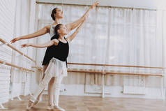 小女孩与老师室内的芭蕾训练。古典芭蕾。巴莱丽娜·图图的女孩。室内训练。可爱的舞者大厅里的表演。舞蹈练习。女孩在白色礼服.