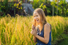 阳光下稻田里摆着植物的年轻女子