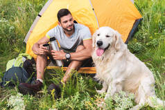 坐在帐篷里看狗的热水瓶的旅行者
