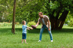 快乐的父亲和儿子在公园玩美式足球