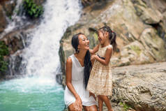 快乐的母亲与她的女儿在热带附近的瀑布。母亲节.