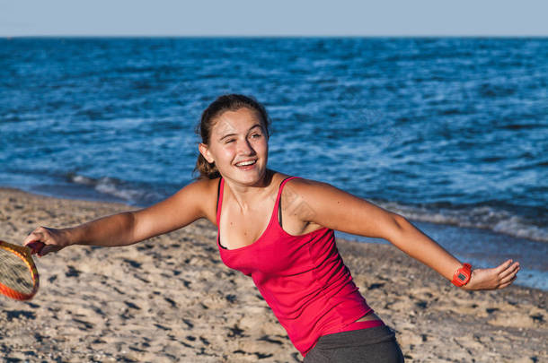 在海滩上打羽毛球的瘦长的晒黑的女孩