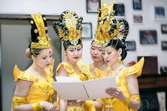 阅读与副本空间为您的文本的空白书的黄色泰国传统服饰的四个亚洲妇女女演员