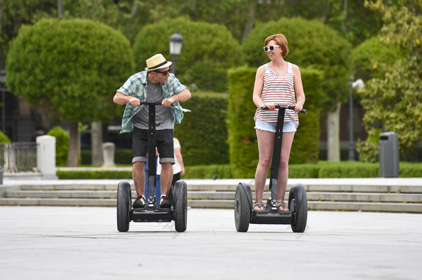 一对年轻快乐的旅游情侣骑着赛格威在西班牙马德里公园享受城市之旅