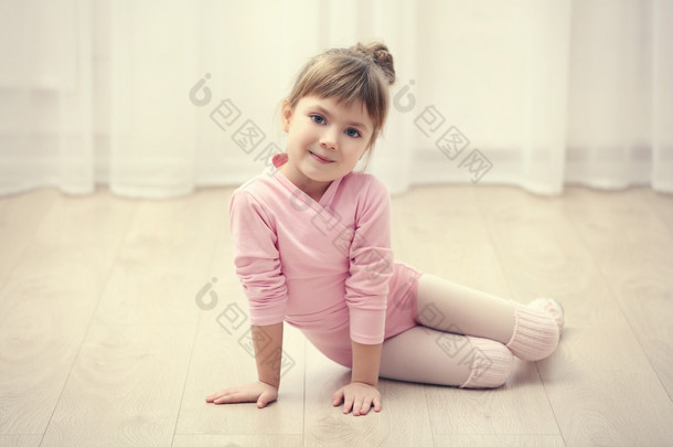 可爱的小女孩在粉红色紧身连衣裤，坐在地板上舞蹈工作室