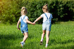 孩子们手牵手在绿草地上奔跑.