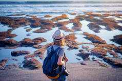 带照相机和背包的年轻旅行妇女海边漫步.