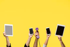 手拿着智能手机, 数字平板电脑和手机在黄色隔离的作物拍摄 