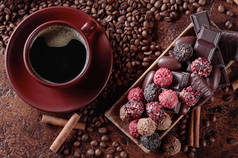 各种巧克力和一杯黑咖啡。有肉桂棒和咖啡豆的糖果放在褐色桌子上。顶部视图.