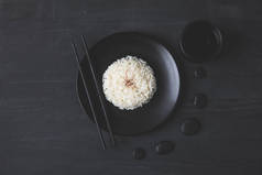黑餐桌上用筷子盘上的美味米饭