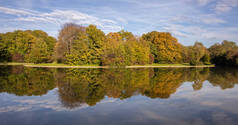 城市公园, 秋季, 慕尼黑, 德国。池塘里的草地、树木和倒影