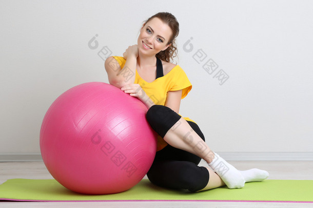 美丽的年轻女子锻炼与健身房球的肖像