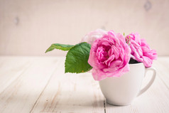 白色的木制背景上的粉红色玫瑰花茶