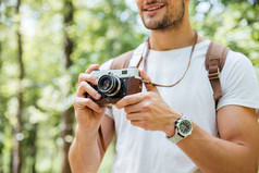 在室外使用老式相机拍照，背包里的男人微笑着