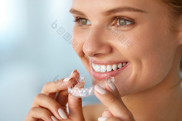 微笑的女人与白色牙齿举行牙齿美白托盘