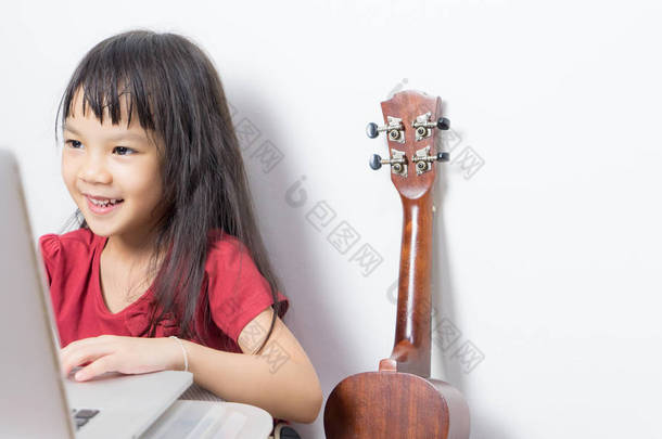 小小<strong>音乐</strong>家孩子正在她在笔记本电脑上的<strong>音乐</strong>。亚洲的孩子正在寻找音<strong>符</strong>上互联网。日本女孩正在吉他<strong>音乐</strong>课程在线.
