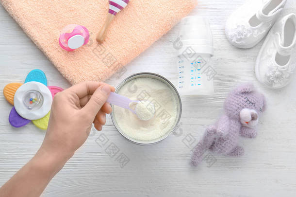 婴儿奶粉用干粉状手持测量勺的妇女 
