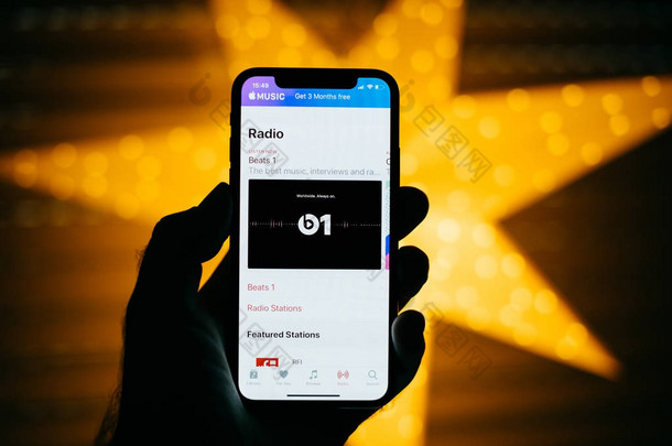 巴黎, 法国-<strong>2017年</strong>11月10日: 人拿着新的苹果 iphone X 10 显示与黄色星散背景以收音机音乐在 itunes 与敲打1