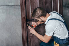 年轻修理工用螺丝刀固定门锁