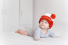 小婴儿的肖像在圣诞老人的帽子躺在床上, 看着远 