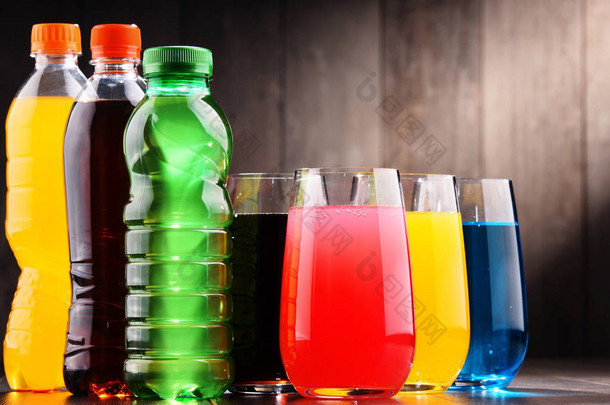 各种颜色的各式碳酸软饮料的玻璃和瓶子