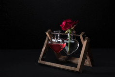红玫瑰在心形花瓶和花瓶的爱情灵药孤立在黑色