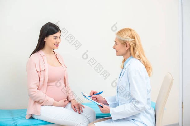 <strong>妇产</strong>科医生咨询孕妇在诊所和书面在剪贴板