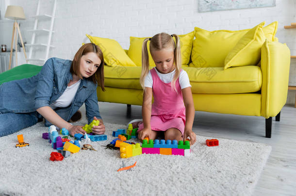 私人幼儿园教师与学龄前女孩一起玩积木游戏