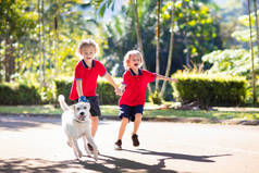儿童走狗。和可爱的小狗玩耍的孩子小男孩和他的宠物一起跑步。孩子们在郊区的街道上玩耍.动物朋友友谊和爱情.