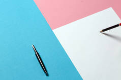 创意商业设计理念。白色纸, 黑色铅笔和一支钢笔在蓝色和粉红色的表面上