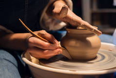 在车间用陶瓷轮雕刻花瓶时，由波特的手进行的特写.
