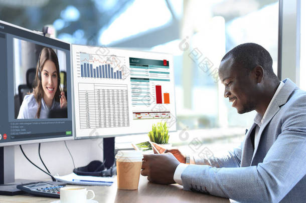 非裔美国商人在视频会议上与他的同事交谈。利用个人电脑在办公室工作的多族裔商业团队，讨论他们公司的<strong>财务报告</strong>.