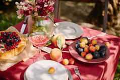 花园餐桌上的成熟水果、酒杯和鲜花花束