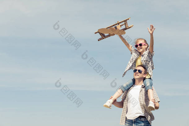 父亲和女儿白天在公园里玩纸板玩具飞机。友好家庭的概念。人们在户外玩得很开心在<strong>蓝天</strong>的背景上拍摄的图片.