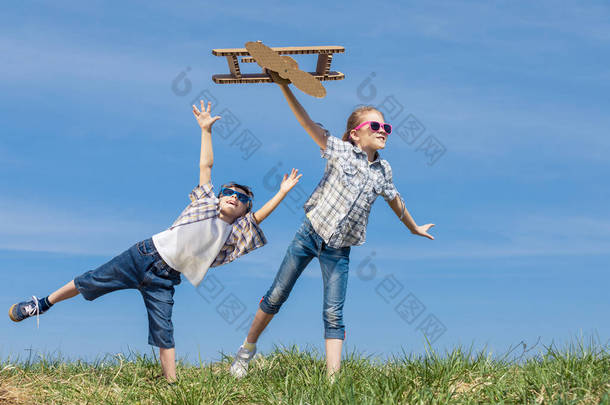 两个小孩白天在公园里玩纸板玩具飞机。快乐游戏的概念。<strong>孩子</strong>们在外面玩得很开心在蓝天的背景上拍摄的图片.