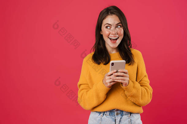 一个快乐的黑发女孩笑着用手机隔离在<strong>粉色背景</strong>下的图片