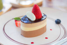 用巧克力酱汁、草莓和白巧克力装饰着光滑的雪纺蛋糕。这道菜用草莓酱、蓝莓和草莓片装饰.