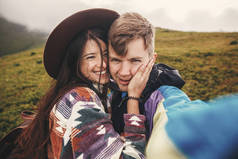 快乐的嬉皮士夫妇制作自拍和微笑在阳光明媚的山顶上。时尚的情侣在爱拍自拍照片, 玩得很开心。一起旅行和流浪欲望的概念.