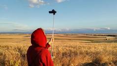小男孩录制了西班牙农业景观的视频。播种的田地里种着小麦和大麦,在地平线上,人们可以看到。欧洲乡村夏日午后的宁静天空.
