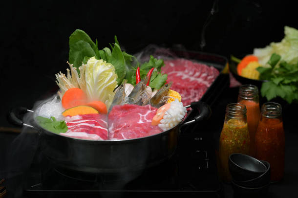 背景为黑色的火锅、鲜切肉、海味食品和蔬菜、日本火锅风格的火锅中的火锅的近景 