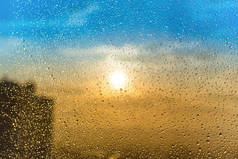 美丽的日落通过飞溅的玻璃与雨水滴和建筑剪影
