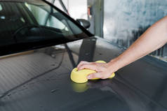 清洁车时手持黄色海绵的男子的裁剪视图 