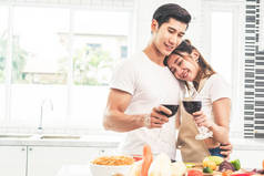 亚洲情侣或情侣在家里的厨房里喝葡萄酒。爱与幸福概念甜蜜的蜜月和情人节主题