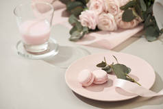 马卡龙在柔和的颜色与粉红色玫瑰花花束在白色的背景。美丽的节日背景。复制空间.