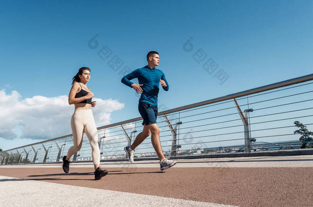 晨练的概念。男子和女子<strong>运动</strong>员在城市一起跑步，使<strong>户外运动</strong>训练的低视角视角